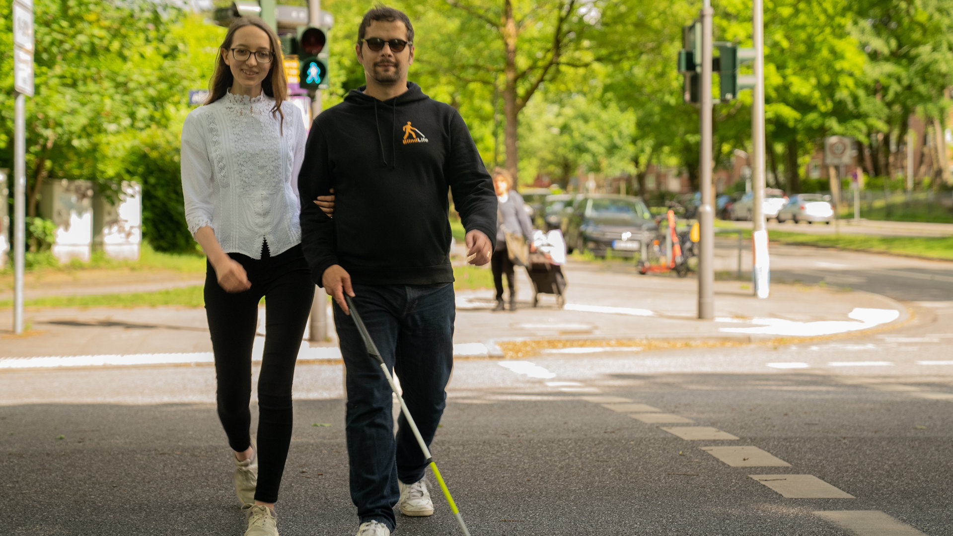 "einfach Mensch : Erdin und Jasmin - Mr. and Mrs. Blindf Life": Erdin und Jasmin, das blinde Pärchen, geht eine Straße entlang.