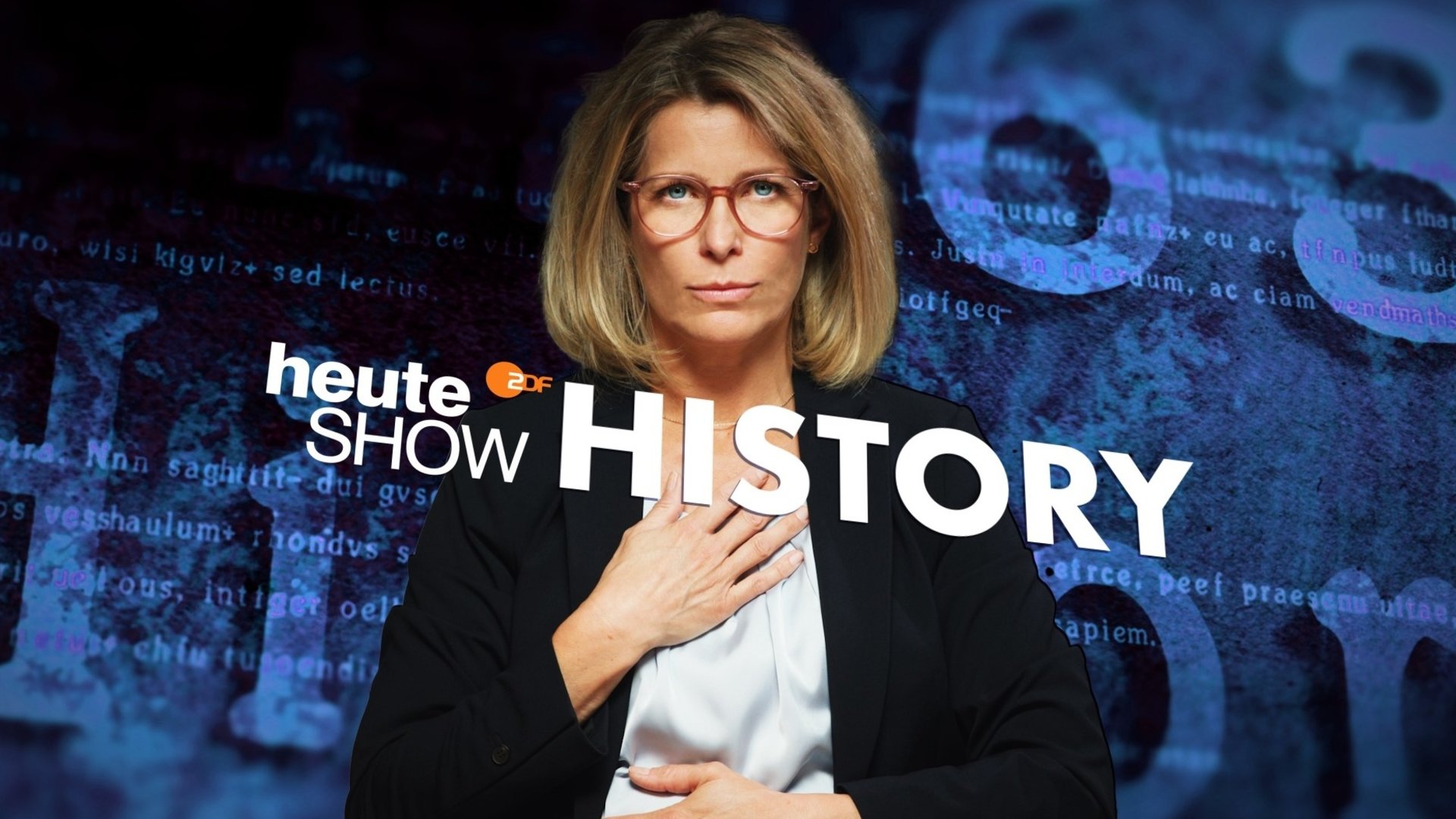 "heute-show history - Oh Mann,... 60 Jahre Frauen im ZDF": Montage: Valerie Niehaus trägt einen schwarzen Blazer und blickt in die Kamera. Sie hält die eine Hand vor ihren Ausschnitt, die andere vor ihren Bauch. Vor ihr liegt das Logo der "heute-show", in der oberen Bildecke ist die Zahl 63.