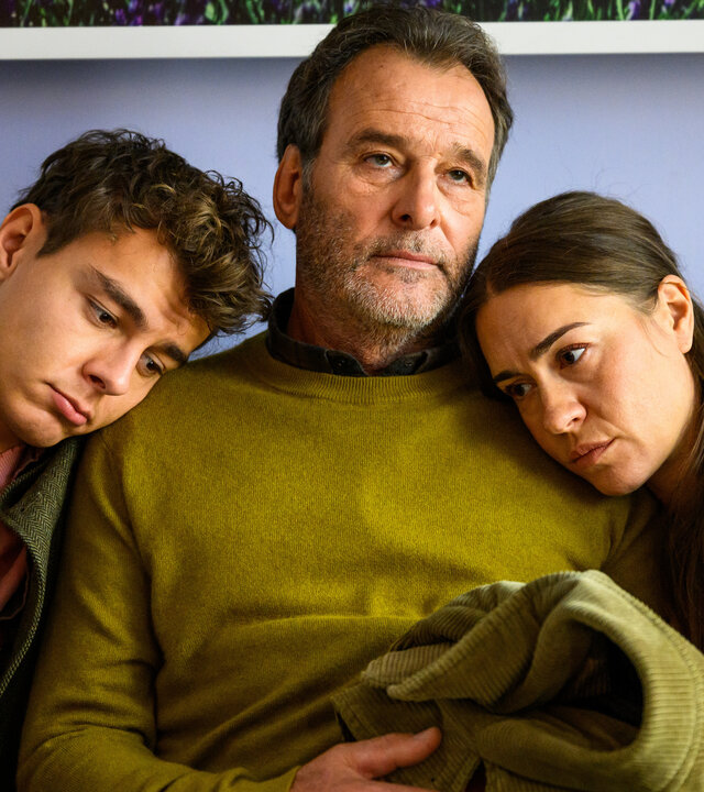 "Bettys Diagnose - Liebe auf BewÃ¤hrung": Simon (Ivan BariÅ¡iÄ) und Betty (Henrike Hahn) sitzen neben ihrem Vater Martin (Joachim Raaf) auf dem Sofa und lehnen sich an seine Schulter. Martin hÃ¤lt eine Jacke in seinen HÃ¤nden.