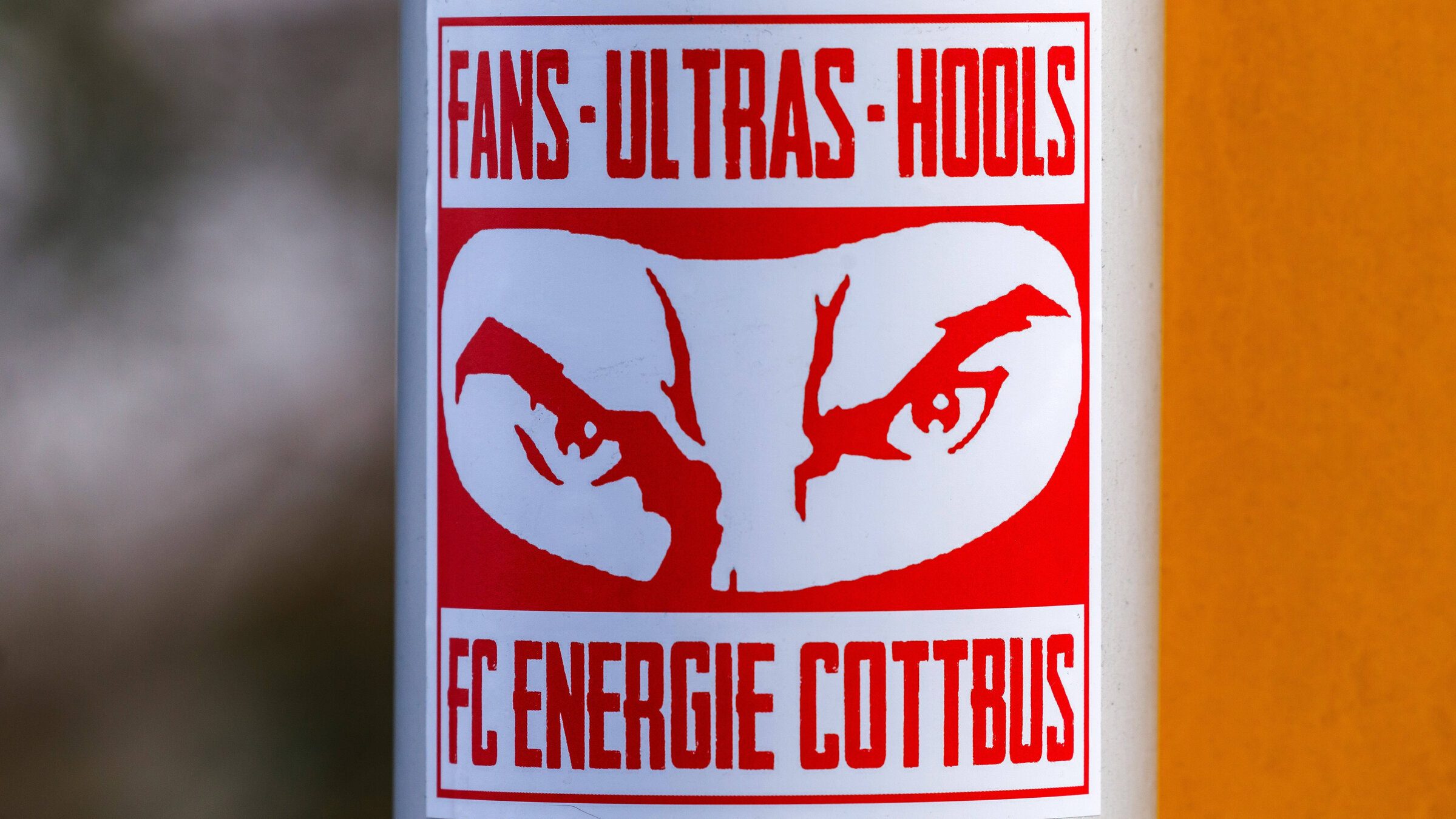 "Inside Fankurve - radikal und extrem": Ein Sticker der Ultras-Fanszene des FC Energie Cottbus klebt auf der Rohrstange eines Verkehrsschildes. Er zeigt in Rot einen maskierten Hooligan und die Aufschrift "Fans, Ultras, Hools - FC Energie Cottbus".
