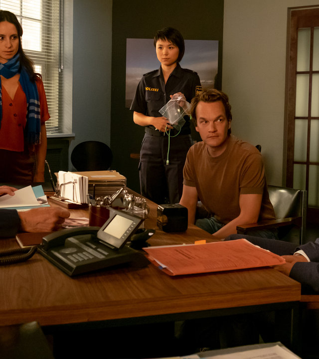 "Der Alte - Zeugen der Anklage": Richard Voss (Jan-Gregor Kremp), Annabell Lorenz (Stephanie Stumph), Julia Lulu Zhao (Yun Huang), Tom Kupfer (Ludwig Blochberger) und Dr. Alexander Spohr (Sebastian Fischer) haben sich rund um Voss'' Schreibtisch versammelt. Alle hören Staatsanwalt Dr. Alexander Spohr gespannt zu.