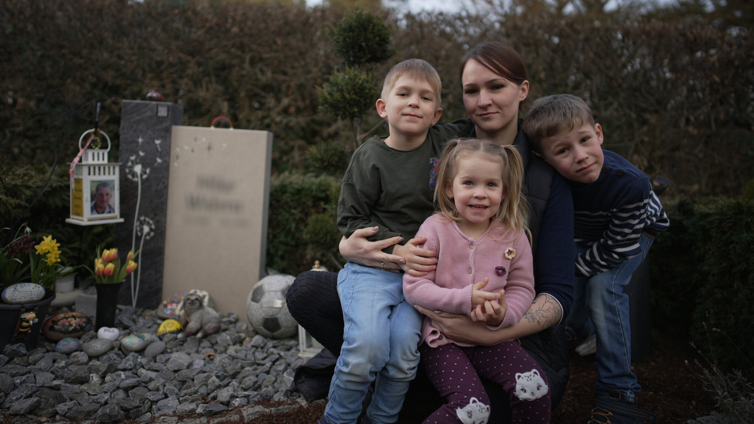 "37°Leben: Aus dem Leben gerissen": Johanna (29) sitzt neben einem Grab. Zwei ihrer Kinder sitzen auf ihren Beinen. Ein kleiner Junge steht in gebeugter Haltung rechts neben ihr, sein Kopf liegt auf ihrer linken Schulter.