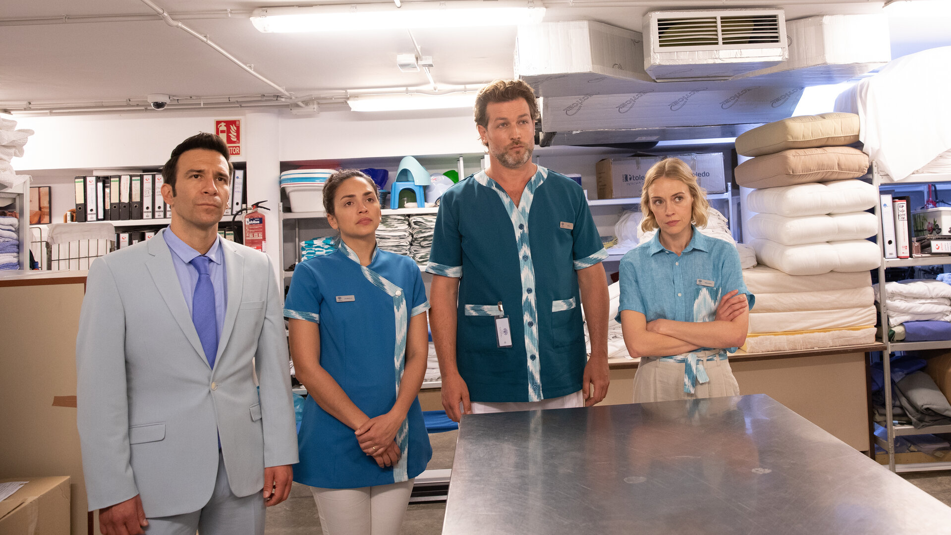 "The Mallorca Files - Undercover": Gustavo (Daniel Ortiz), Isabella (Amanda Vilanova), Max (Julian Looman) und Miranda (Elen Rhys) stehen in der Wäscherei des Resorts und blicken ernst geradeaus.