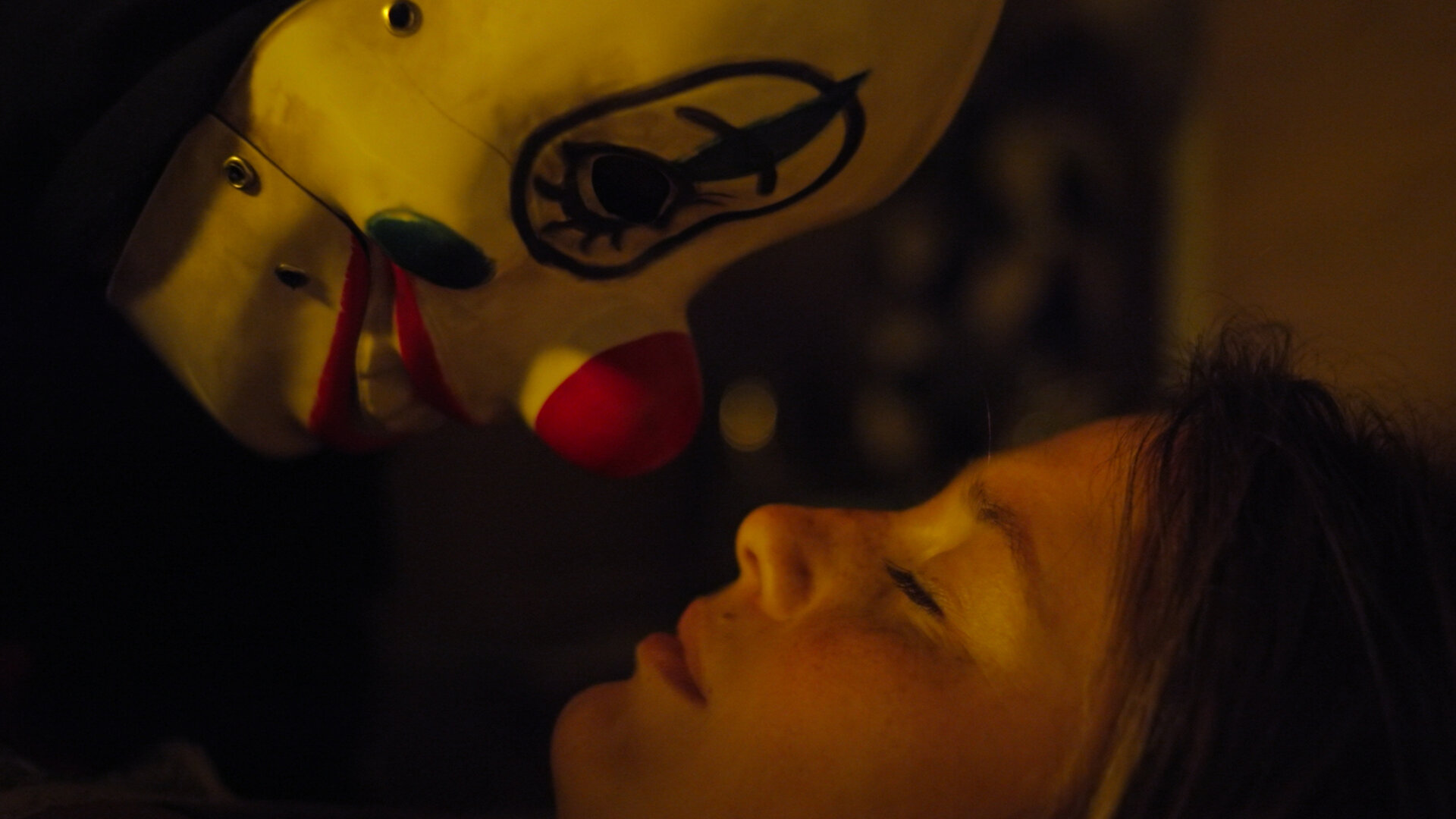 "Notruf Hafenkante - Besuch in der Nacht": Großaufnahme: Der Kopf der schlafenden Mina (Bianca Nawrath) liegt auf dem Bett, nah über ihrem Kopf ist der Kopf eines Mannes, der eine Clownsmaske trägt. Es schaut sie an.