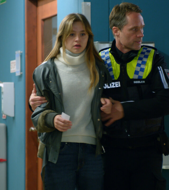 "Notruf Hafenkante - Gefährliche Mission": Der Polizist Mattes Seeler (Matthias Schloo) geht mit Michelle (Flora Li Thiemann) über den Gang des Elbkrankenhauses. Er hat seinen rechten Arm um Michelle gelegt und stützt sie. Michelle schaut entsetzt.