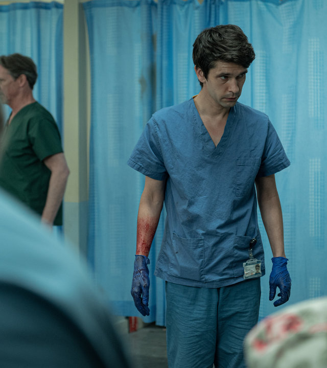 "This Is Going To Hurt - Glück im Unglück": Adam (Ben Whishaw) steht im Gang einer Krankenstation und schaut besorgt auf den Boden. Dabei trägt er seine Arztklamotten und hat Gummihandschuhe übergezogen.