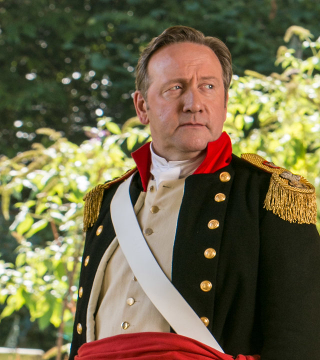 "Inspector Barnaby - Stolz, Mord und Vorurteil": DCI John Barnaby (Neil Dudgeon) steht in einem prunkvollen Kostüm aus der Regency-Epoche an einem Herrenhaus.