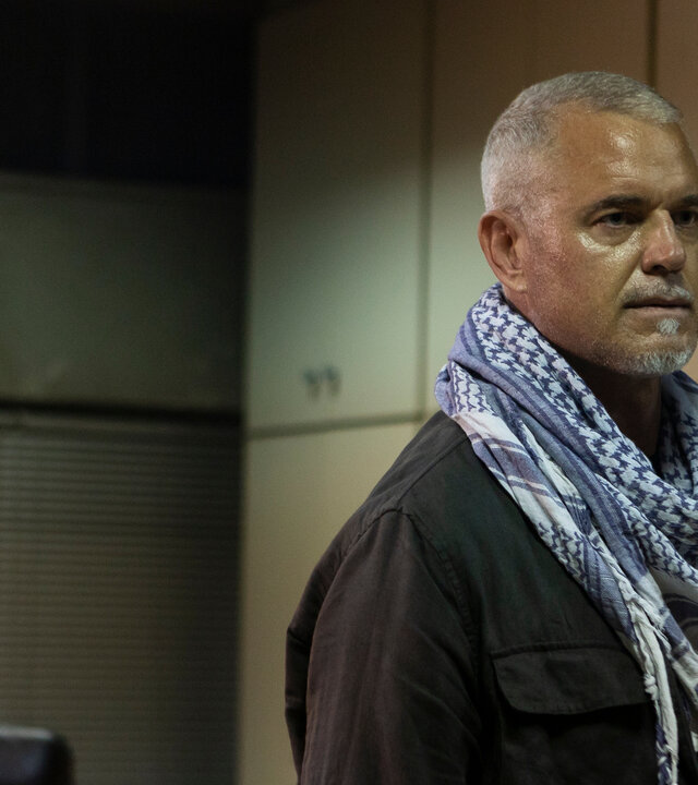 "Kabul - Flucht aus der Hölle: Ungewöhnliche Weggefährten": Martin (Eric Dane) steht im Rahmen der Glastür zu einem Büro und schaut ernst zur Seite. Er trägt ein typisches afghanisches Tuch um den Hals.