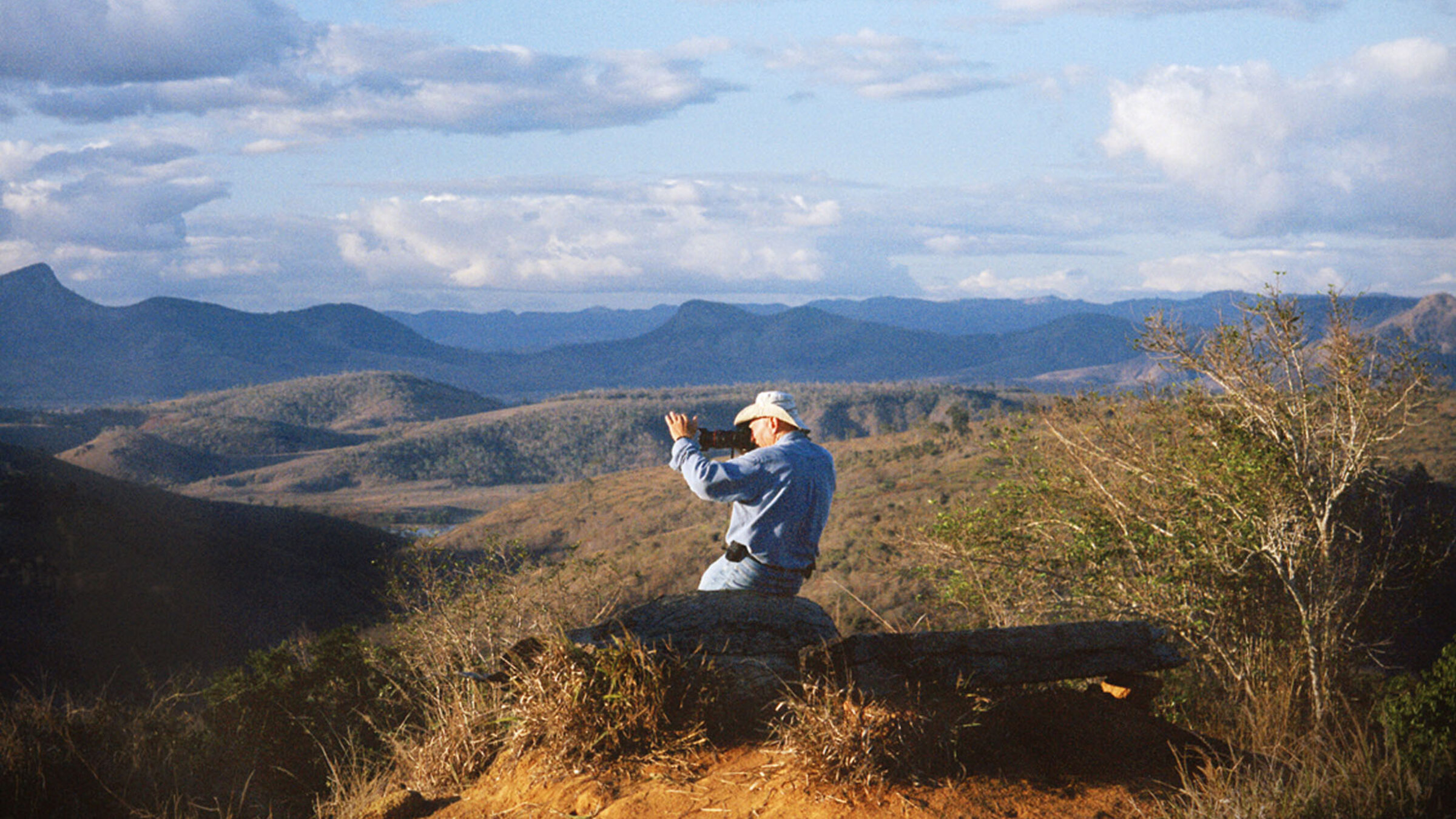 "Das Salz der Erde": Totale: Mann sitzt vor eindrucksvoller Landschaft unter blauem Himmel.