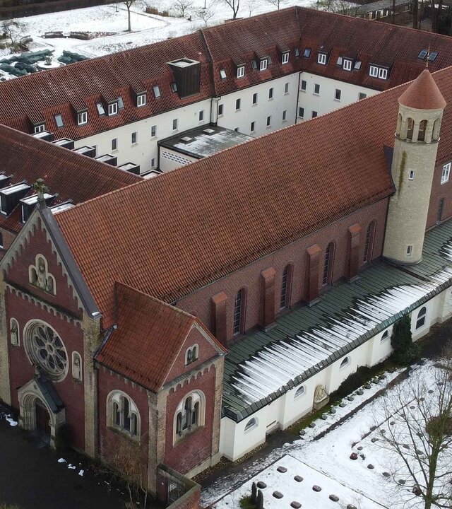 "Katholischer Gottesdienst - Im Licht wird alles mehr": Luftbild: Das Kapuzinerkloster in Münster mit seiner angeschlossenen Kapuzinerkirche auf der rechten Seite liegt inmitten schneebedeckter Grünflächen.