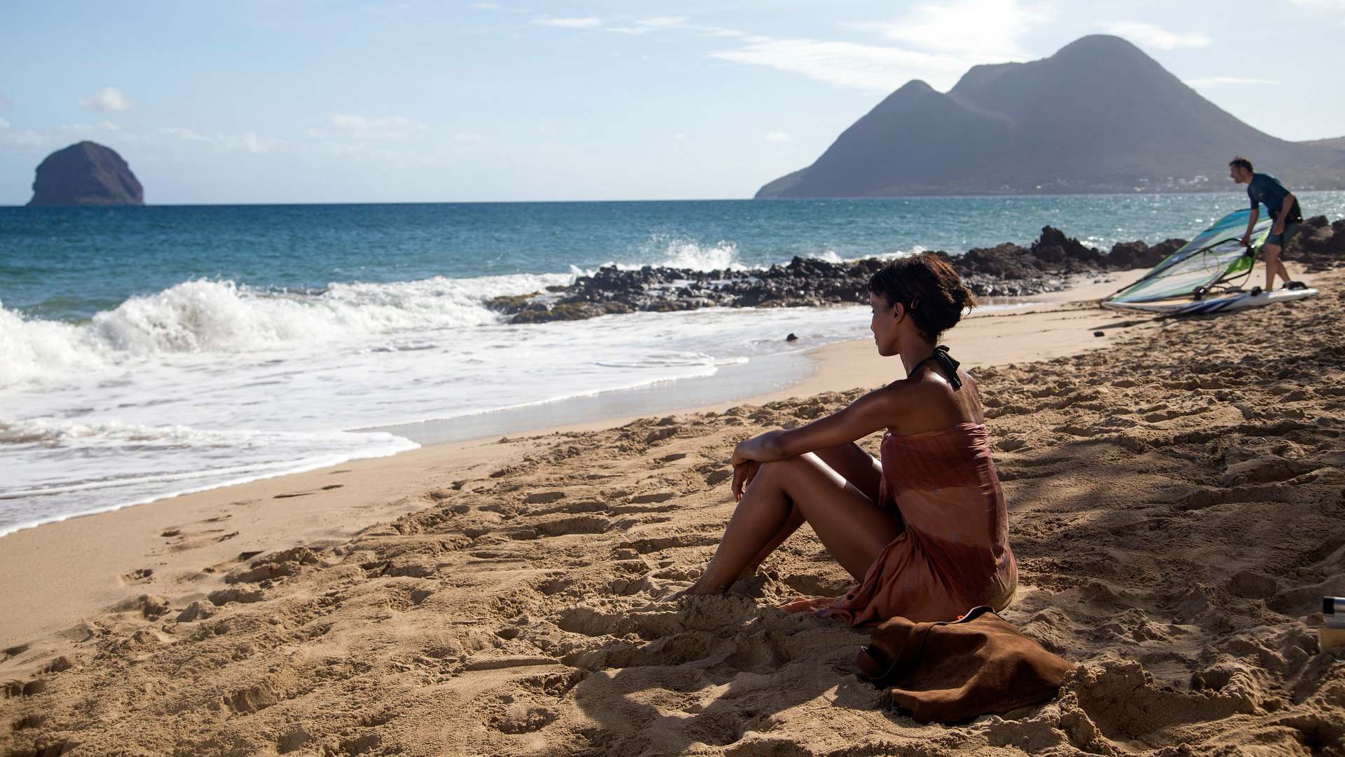 "Deadly Tropics - Götterdämmerung": Mélissa Sainte-Rose (Sonia Rolland) sitzt im Bikini am Strand und blickt auf das Meer.