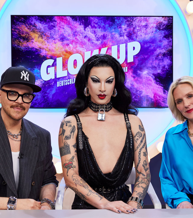 "Glow Up - Deutschlands nächster Make-up-Star": Stammjury Armin Morbach und Loni Baur sitzen mit Gastjurorin und Dragqueen Violet Chachki am Jurypult im Glow-up-Headquarter.
