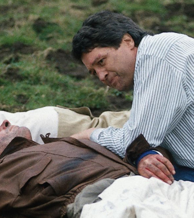 "Der Landarzt - Ein Kind wird vermisst": Dr. Mattiesen (Christian Quadflieg) kniet neben dem verletzten Piloten (Peter Hick) auf einer Wiese und versorgt ihn.