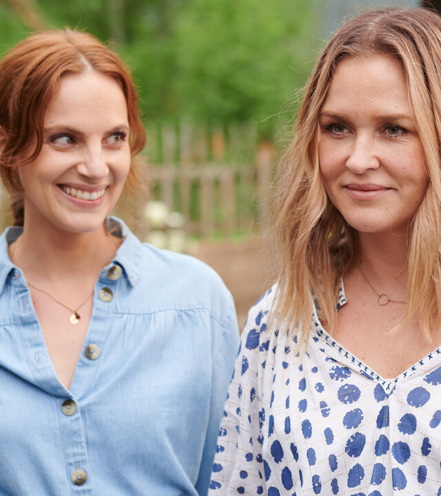 "Lena Lorenz - Zerbrechliches Glück (2)": Bettine Zunhammer (Marie Zielcke) steht neben Lena Lorenz (Judith Hoersch) im Freien und schaut diese strahlend an.