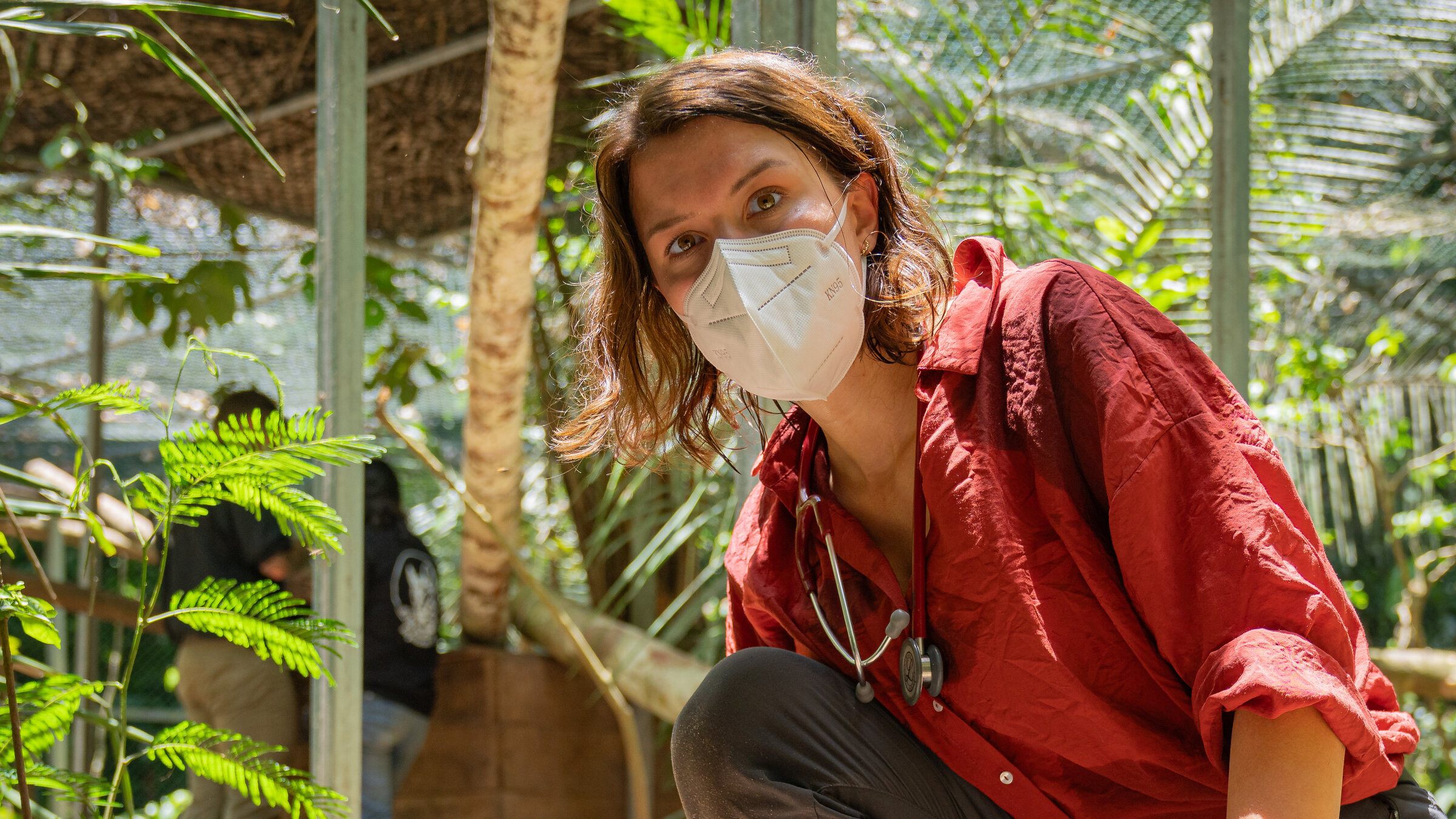 "Terra X: Faszination Erde – mit Hannah Emde: Peru – Ein Land, vier Welten": Hannah Emde kniet im Freien neben einem Jaguar, der auf einer Decke liegt. Sie trägt einen Mundschutz und schaut in die Kamera.