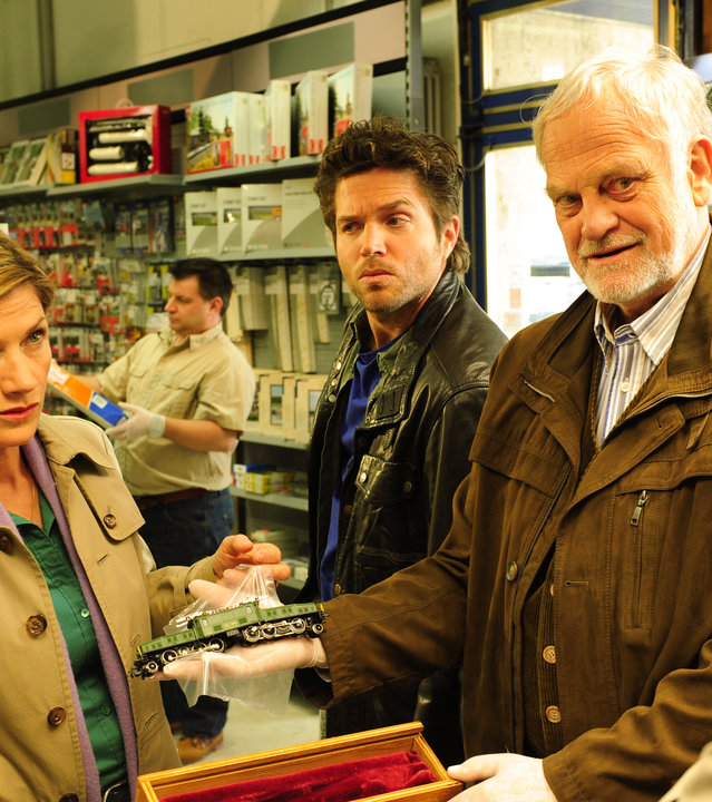 "SOKO Stuttgart - Krokodil": Martina Seiffert (Astrid M. Fünderich), Jo Stoll (Peter Ketnath), Friedemann Sonntag (Christian Paetzold) und Gerhard Wendt (Lutz Herkenrath) stehen zusammen in einem Laden und Friedemann Sonntag hält einen Gegenstand in der Hand. Im Hintergrund steht ein weiterer Spurensicherer.