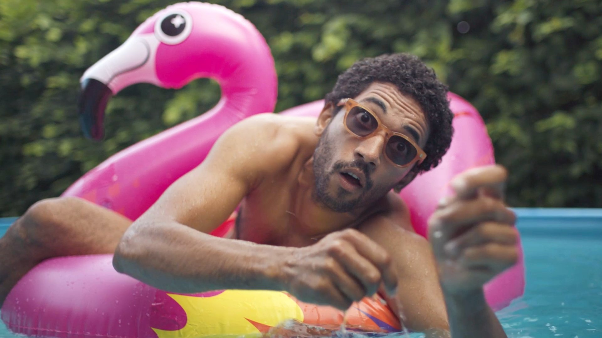 "Doppelhaushälfte - Schall und Rauch": Theo (Benito Bause) sitzt in einem pinkfarbenen aufblasbaren Riesenflamingo im Pool und blickt erschrocken.