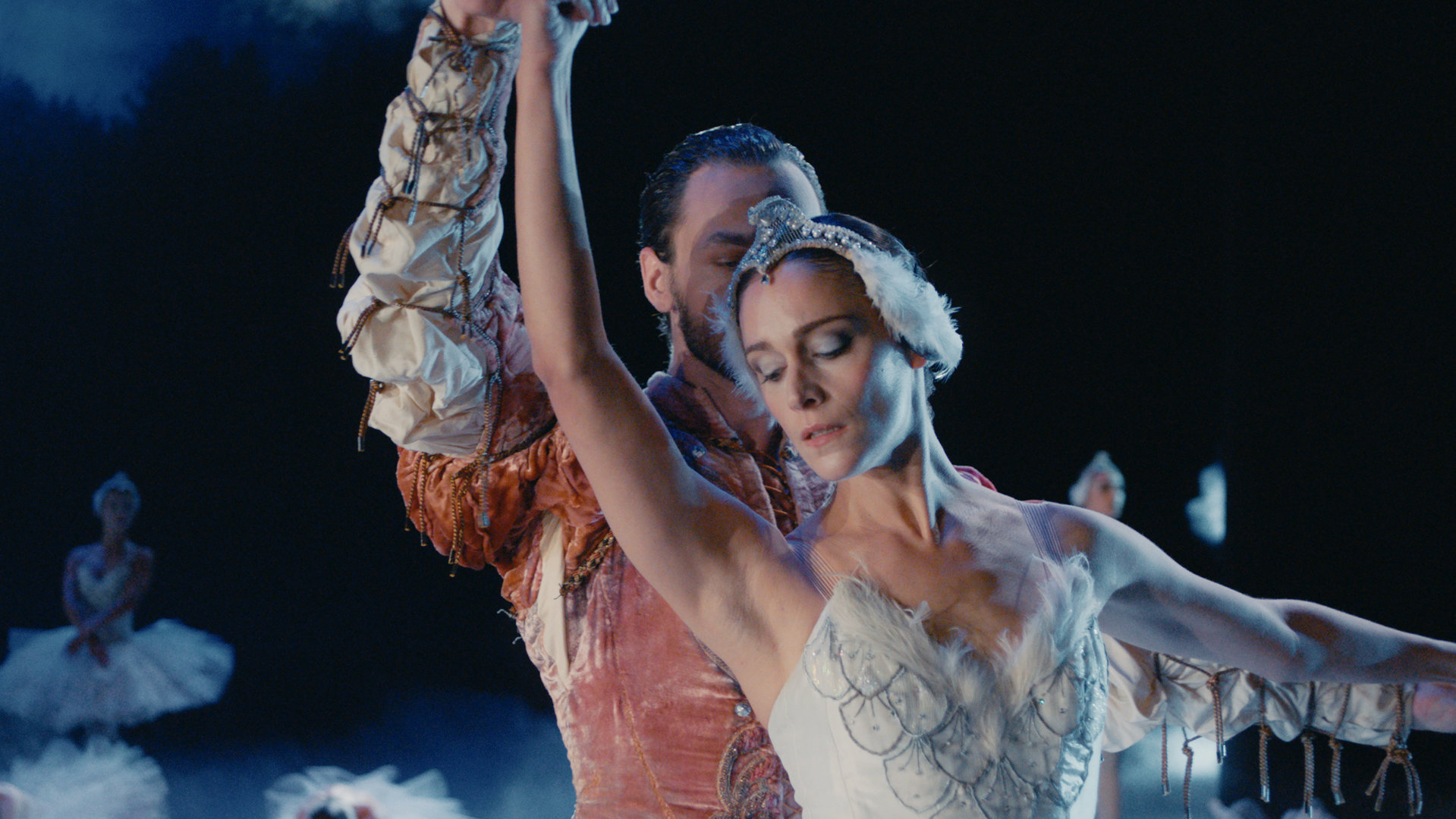 "L' Opéra - Dancing in Paris - Weg zurück": Jonas (Loris Freeman) steht auf einer Bühne dicht hinter Zoé (Ariane Labed) im Scheinwerferlicht. Beide sind kostümiert und tanzen einen Abschnitt aus Schwanensee.