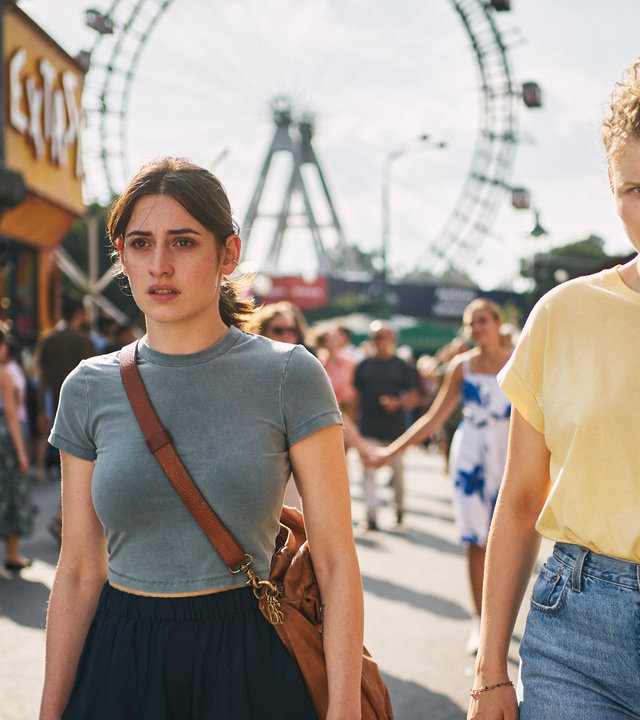 "Der Schatten - Schuld": Norah Richter (Deleila Piasko) und Theresa Winkler (Luisa-Céline Gaffron) laufen gemeinsam über den Wiener Prater. Sie schauen um sich. Im Hintergrund sind viele Menschen und das Wahrzeichen, das Riesenrad, zu sehen.