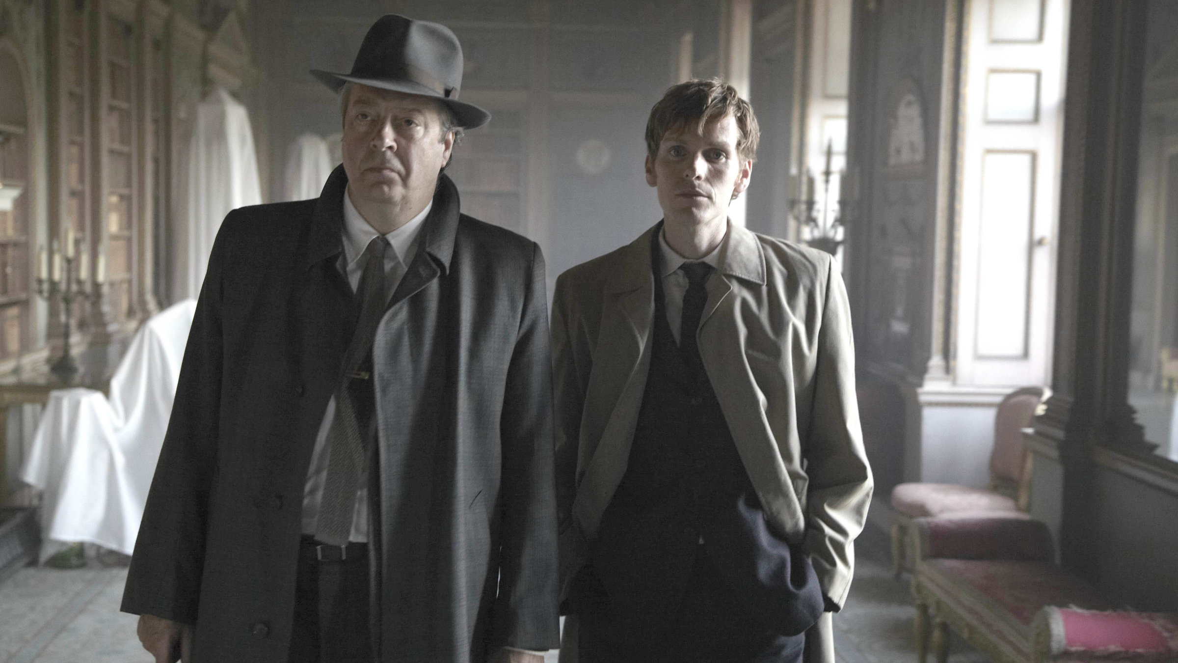 "Der junge Inspektor Morse - Ein Gedicht": Fred Thursday (Roger Allam) und Endeavour Morse (Shaun Evans) laufen nebeneinander einen Flur in einem Schloss entlang.