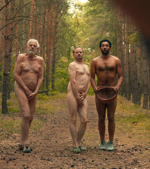 "Doppelhaushälfte - Die Zone": Andis Vater Ingo (Christian Pätzold), Andi (Milan Peschel) und Theo (Benito Bause) stehen nackt nebeneinander im Wald. Sie verdecken ihr Geschlecht mit den Händen, Theo mit einem Korb.