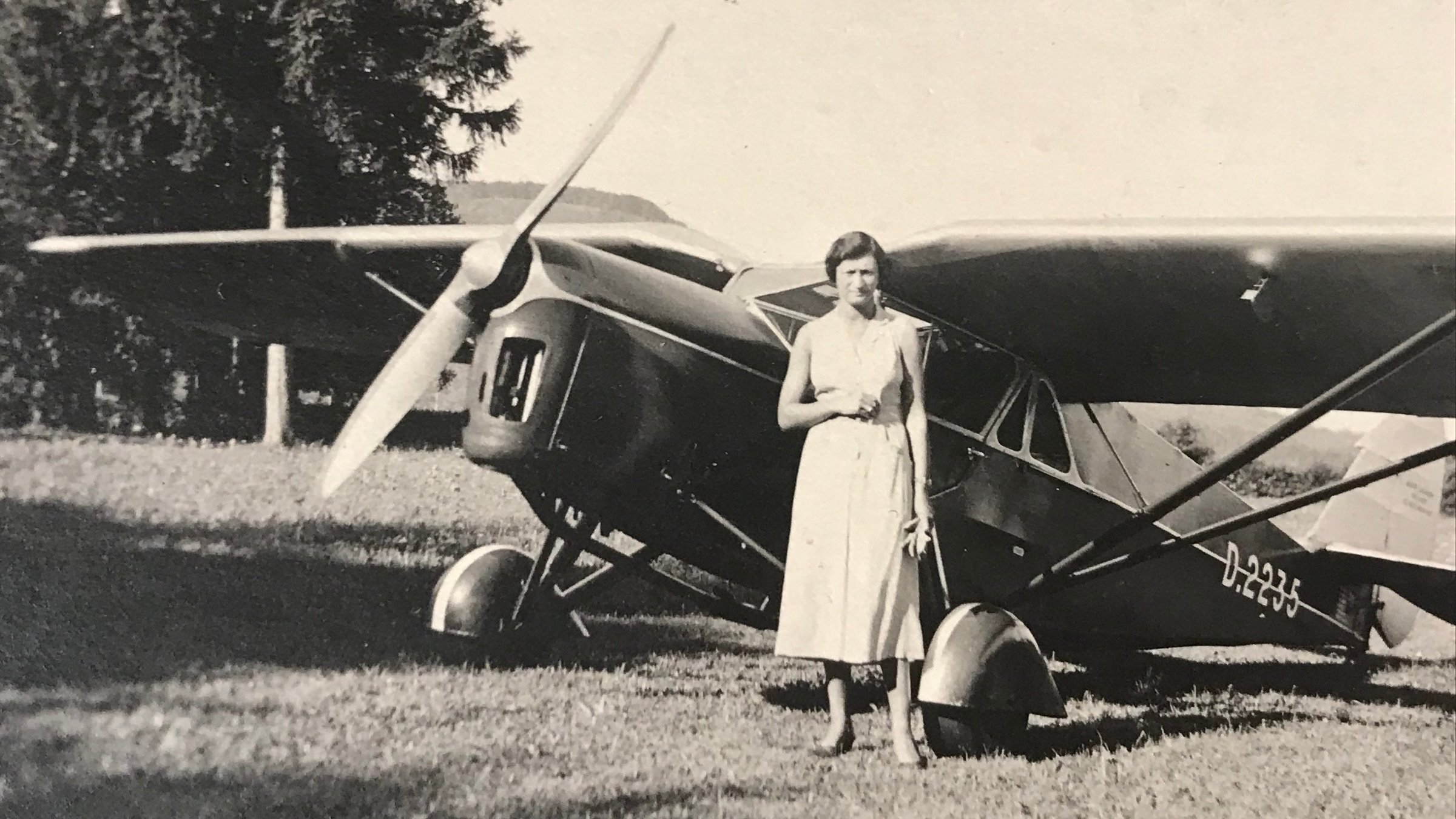 "Geraubte Kunst - Jüdische Sammlungen im Nationalsozialismus": Schwarz-Weiß-Foto: Agathe Saulmann steht in einem Sommerkleid vor einem Leichtflugzeug und blickt in die Kamera.