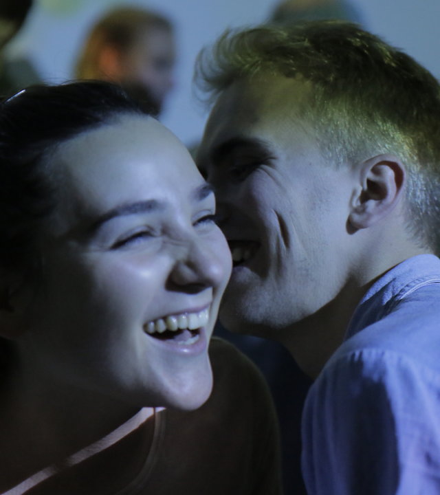 "About Saturday - Der Barkeeper": Klara (Darin Hagi) HM (William Greni Arnø) tanzen in einem Club eng zusammen auf einer Tanzfläche inmitten vieler Menschen. Klara lacht, während HM ihr etwas ins Ohr flüstert.